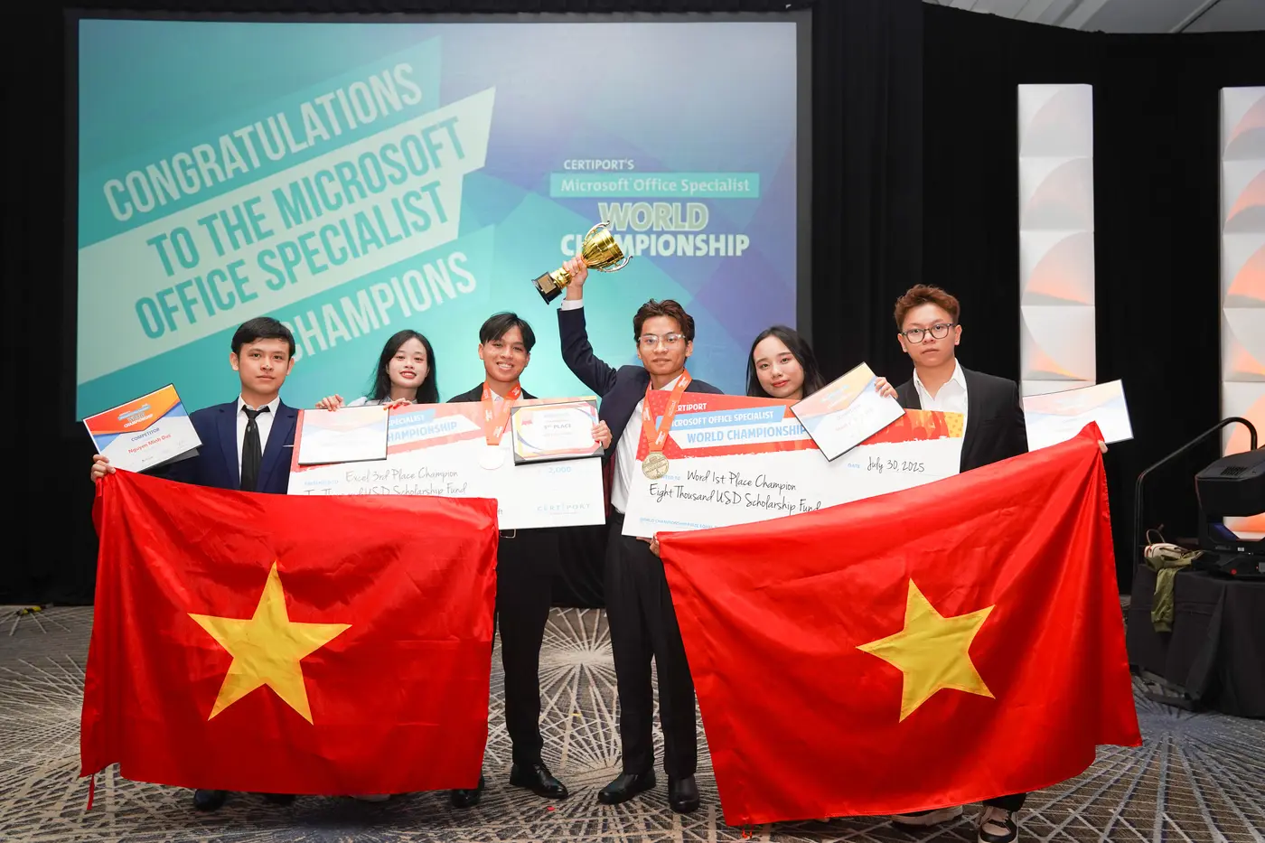 Vietnamese contestants holding the national flag and certificates on stage at the Microsoft Office Specialist World Championship